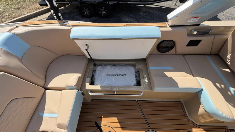 Slide: The Image of 2025 MasterCraft X26 boat interior with tan and blue seating, open storage compartment. - 17