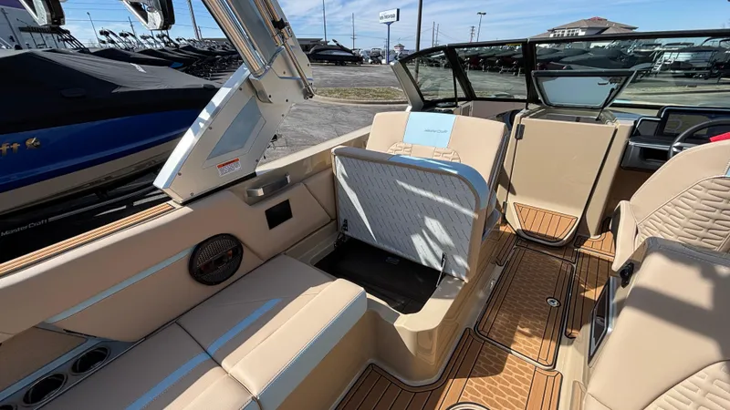 Slide: The Image of 2025 MasterCraft X26 boat interior with beige seating and open storage compartment. - 21