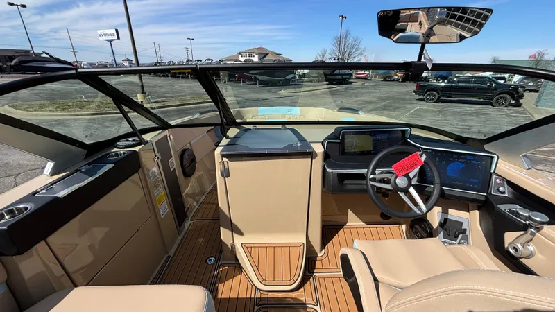 Slide: The Image of 2025 MasterCraft X26 boat interior with modern dashboard and steering wheel, parked outdoors. - 31