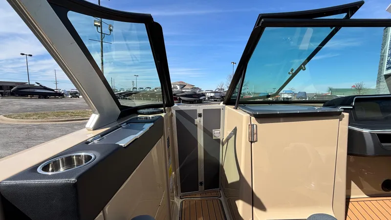 Slide: The Image of 2025 MasterCraft X26 boat interior with open windshield and cup holder, parked outdoors. - 33