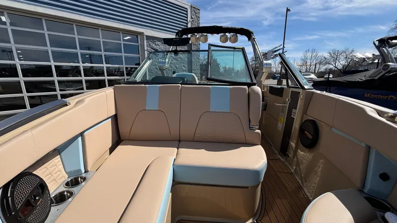 Slide: The Image of 2025 MasterCraft X26 boat interior with beige and blue seating, docked outdoors. - 37