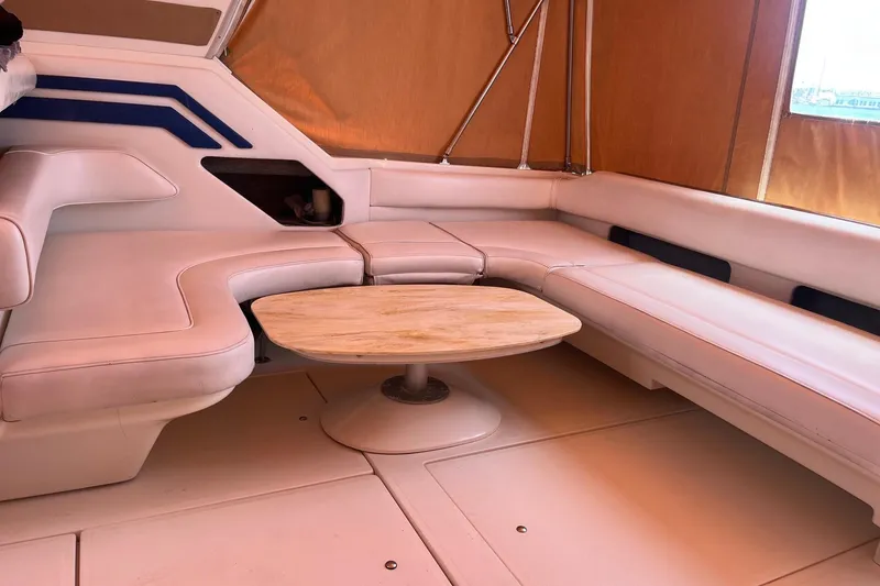 Slide: The Image of Luxurious interior of 1994 Sea Ray 400 Express Cruiser with plush seating and wooden table. - 4