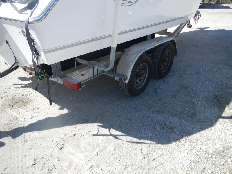 Slide: The Image of 2016 Sea Hunt Ultra 234 boat on a dual-axle trailer, parked on gravel. - 6