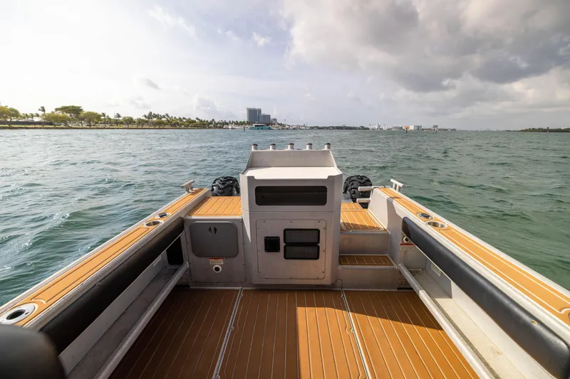 Slide: The Image of Sealegs 8.5M 2022 boat on water, wooden deck, cloudy sky, distant shoreline. - 9