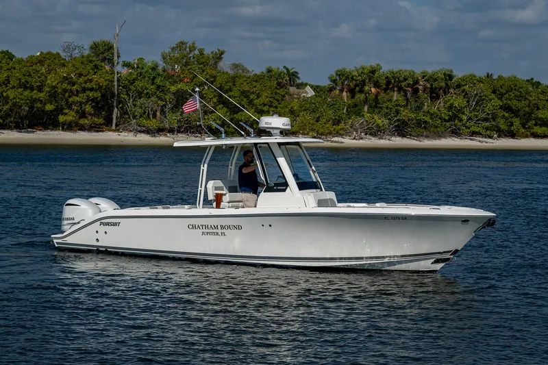 Slide: The Image of 2021 Pursuit S 288 Sport boat cruising on a calm waterway with lush greenery in the background. - 10