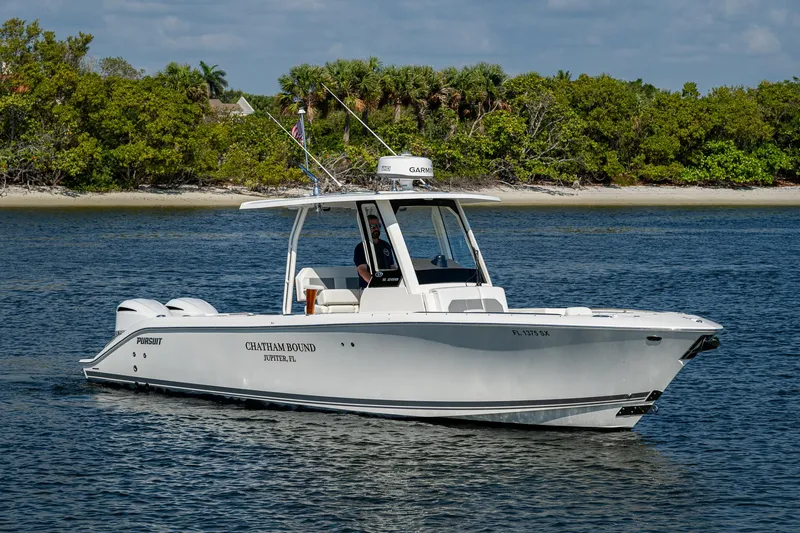 Slide: The Image of 2021 Pursuit S 288 Sport boat cruising on calm water near lush shoreline. - 11