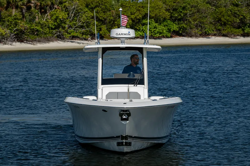 Slide: The Image of 2021 Pursuit S 288 Sport boat cruising on calm water near a lush shoreline. - 12