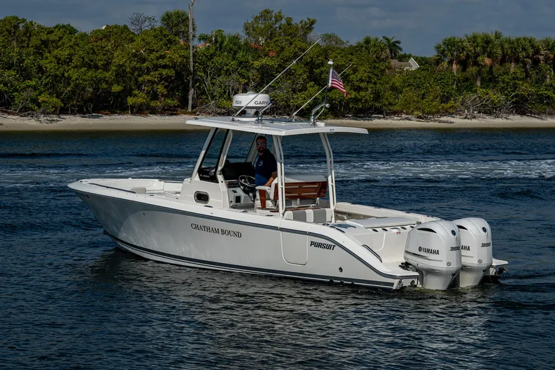 Slide: The Image of 2021 Pursuit S 288 Sport boat cruising on water with twin engines and American flag. - 13