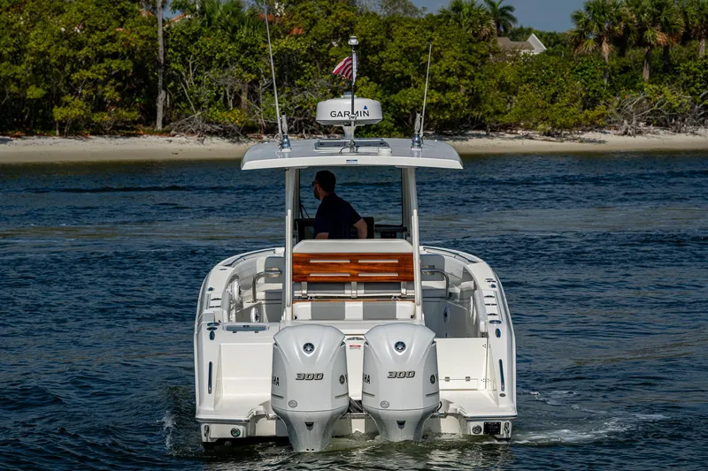 Slide: The Image of 2021 Pursuit S 288 Sport boat cruising near a lush shoreline. - 15