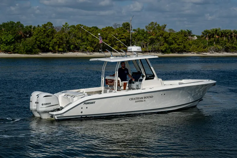 Slide: The Image of 2021 Pursuit S 288 Sport boat cruising on a calm river with lush green shoreline. - 17