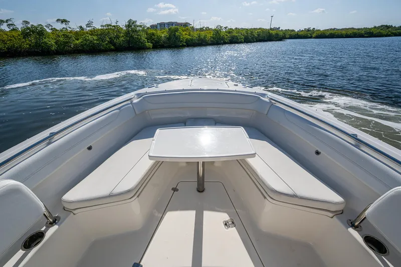 Slide: The Image of 2021 Pursuit S 288 Sport boat interior with seating and table on calm water. - 19