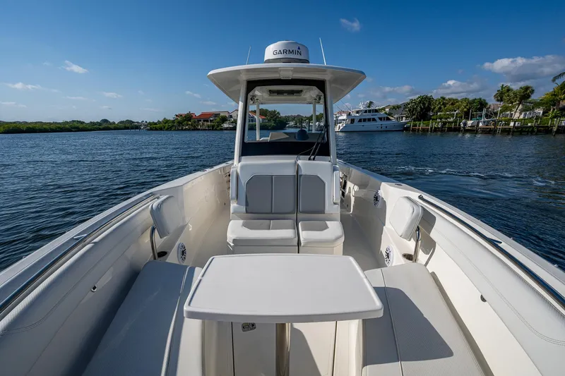Slide: The Image of 2021 Pursuit S 288 Sport boat on calm water, featuring spacious seating and table. - 23