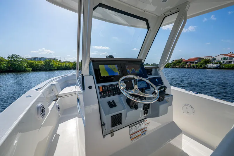 Slide: The Image of 2021 Pursuit S 288 Sport boat cockpit with steering wheel and navigation system on a sunny day. - 31