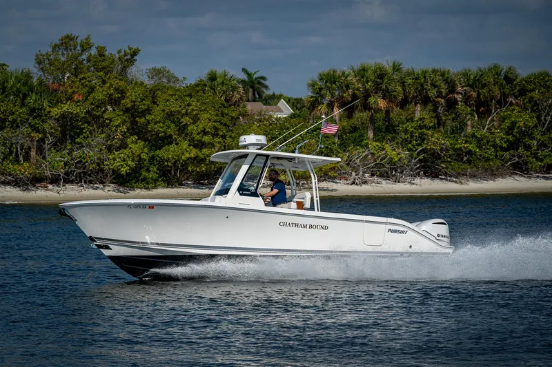 Slide: The Image of 2021 Pursuit S 288 Sport boat cruising on water near lush shoreline. - 6