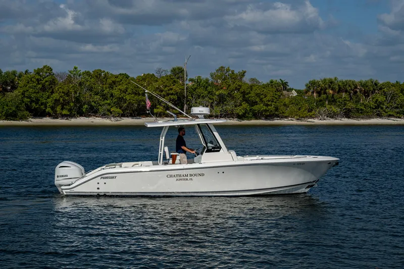 Slide: The Image of 2021 Pursuit S 288 Sport boat cruising on a calm waterway with lush greenery in the background. - 9