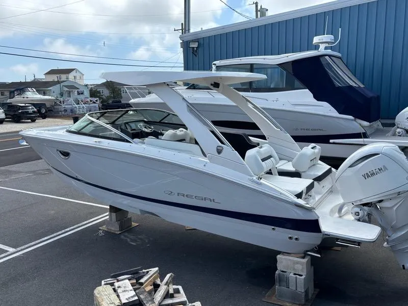 Slide: The Image of 2026 Regal LX6 boat with Yamaha engine, parked outdoors near blue building. - 2