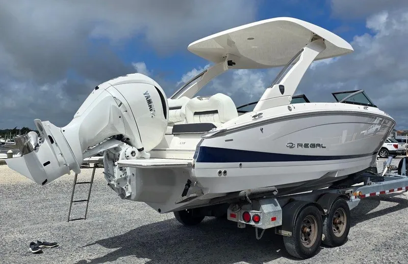 Slide: The Image of 2026 Regal LX6 boat on trailer with Yamaha outboard motor, under cloudy sky. - 7