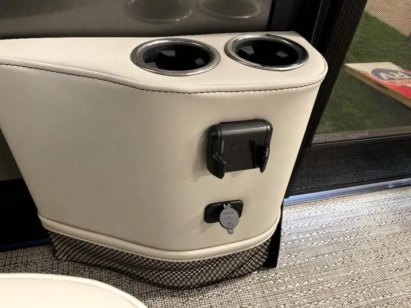 Slide: The Image of 2024 Lusso Ultra-Lounge 25UC cup holders and charging port on beige interior. - 24