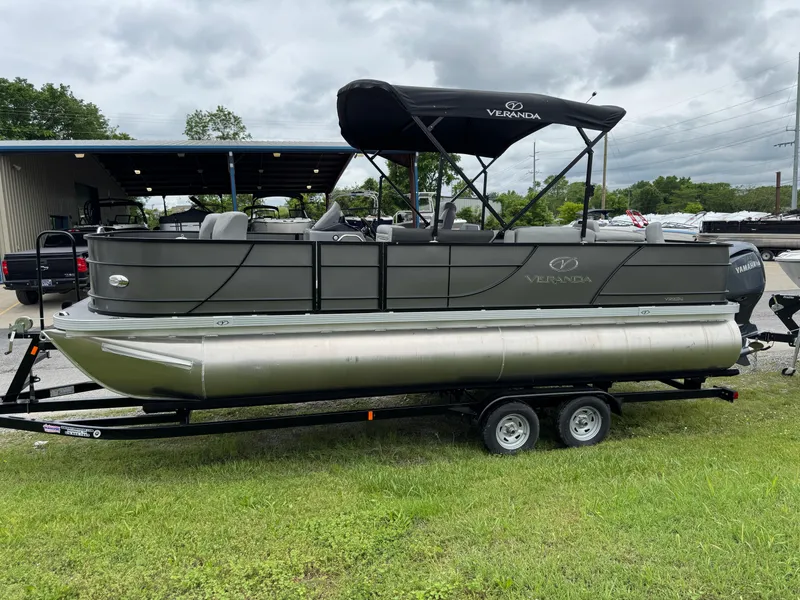 Slide: The Image of 2025 Veranda Fish VF22F4 pontoon boat on trailer, parked on grass under cloudy sky. - 0