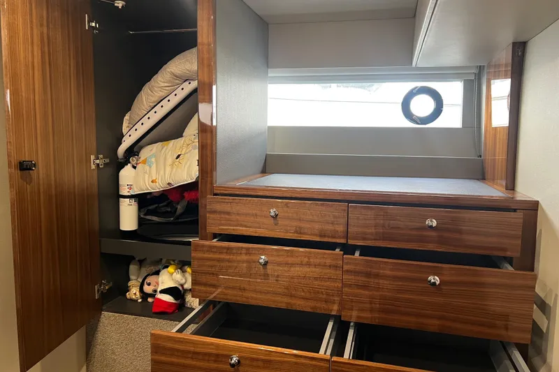 Slide: The Image of 2020 Maritimo M51 yacht interior with wooden cabinets and drawers, featuring a porthole window. - 107