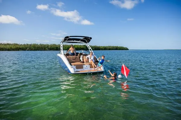 Slide: The Image of 2025 Yamaha Boats 252SD on water with people swimming nearby, under clear blue sky. - 4
