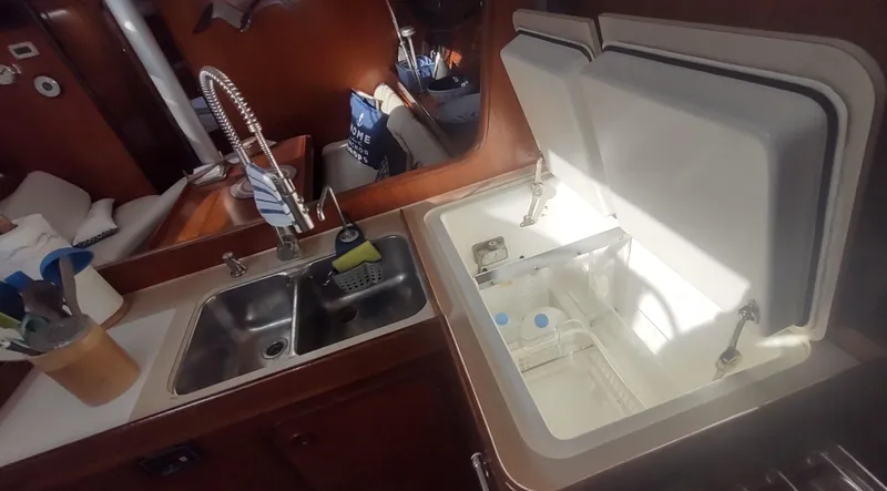 Slide: The Image of Interior of 1990 Beneteau Oceanis 390 yacht kitchen with sink and open storage compartment. - 15
