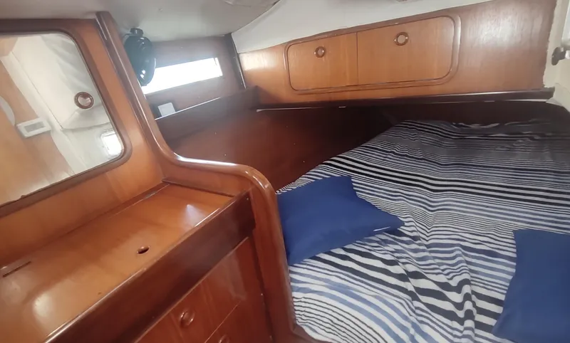 Slide: The Image of Cozy cabin interior of 1990 Beneteau Oceanis 390 sailboat with wood finish and striped bedding. - 19