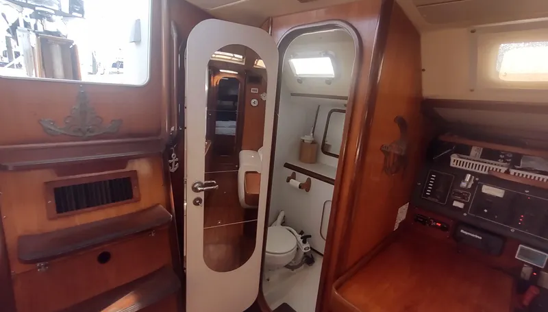 Slide: The Image of Interior of 1990 Beneteau Oceanis 390 sailboat, featuring wooden cabinetry and compact bathroom. - 22