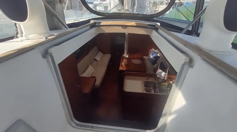 Slide: The Image of Interior view of 1990 Beneteau Oceanis 390 sailboat, featuring cozy seating and compact kitchen area. - 5