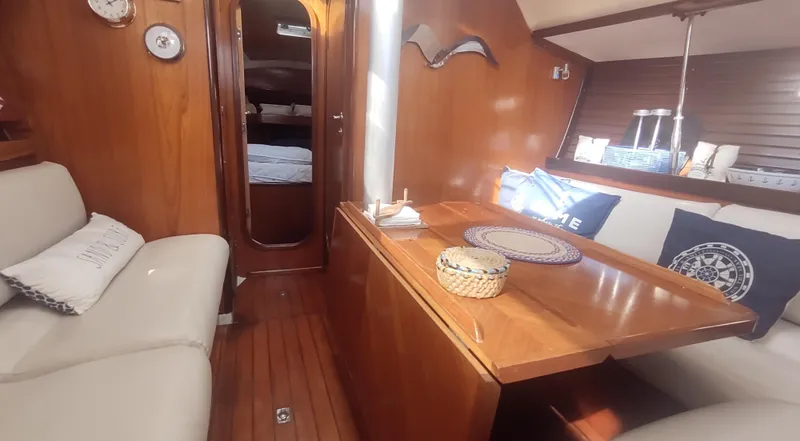 Slide: The Image of Interior of 1990 Beneteau Oceanis 390 sailboat with wooden furnishings and cozy seating area. - 7