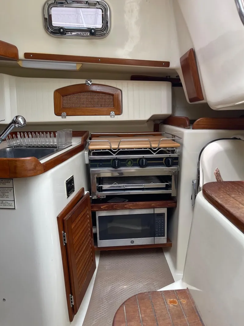 Slide: The Image of 2005 Hake Seaward 32RK yacht kitchen with stove, microwave, and wooden cabinetry. - 19