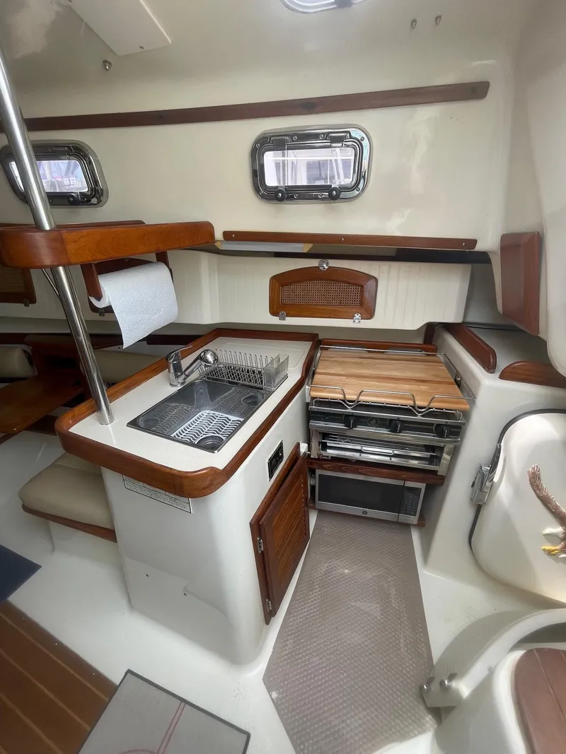 Slide: The Image of 2005 Hake Seaward 32RK yacht interior with compact kitchen, sink, stove, and wooden accents. - 20