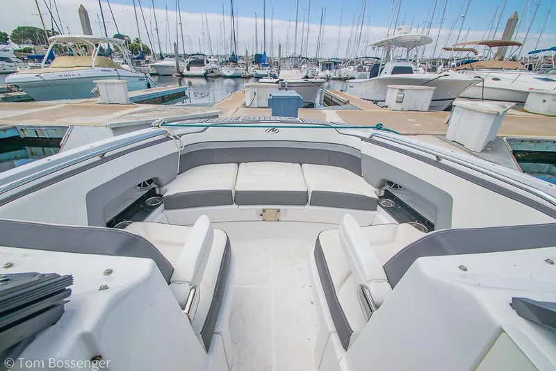 Slide: The Image of 2018 Monterey MX6 Surf Edition boat interior at marina, showcasing seating and docked boats. - 21