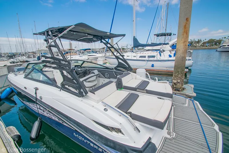 Slide: The Image of 2018 Monterey MX6 Surf Edition boat docked in a marina, surrounded by sailboats. - 7