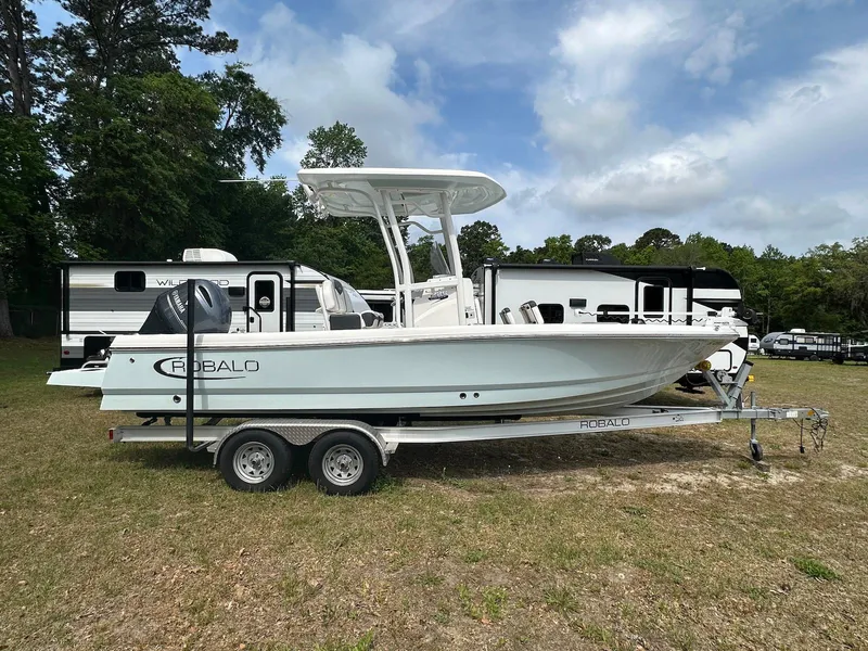 The Image of 2023 Robalo 226 Cayman boat on trailer, parked outdoors near RVs. - 0