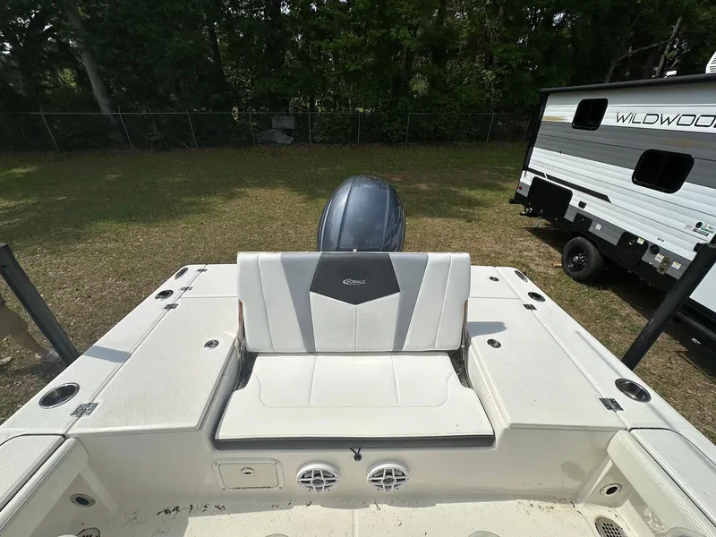 Slide: The Image of 2023 Robalo 226 Cayman boat interior with seating and motor, parked near a camper. - 10
