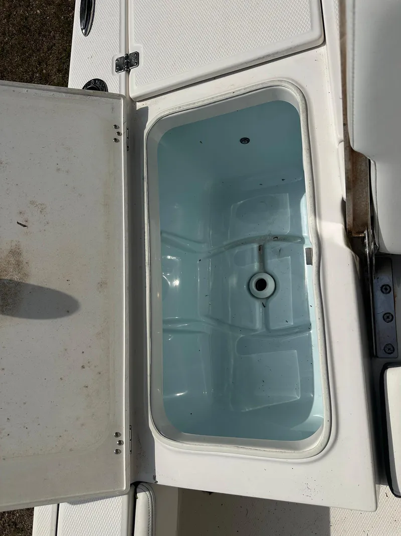 Slide: The Image of 2023 Robalo 226 Cayman boat storage compartment, open lid, white interior. - 14