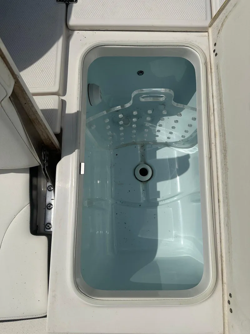 Slide: The Image of 2023 Robalo 226 Cayman livewell, open lid, white interior, boat accessory. - 16