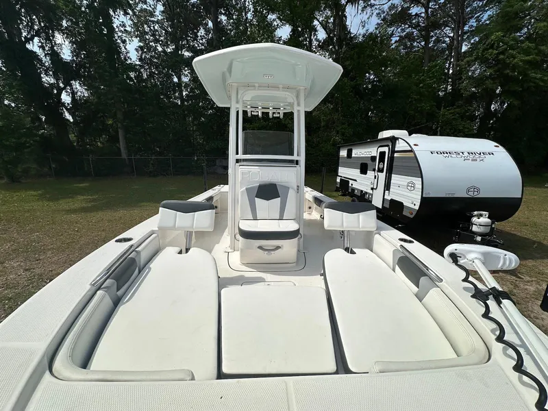 Slide: The Image of 2023 Robalo 226 Cayman boat with spacious seating, parked near a camper in a wooded area. - 7