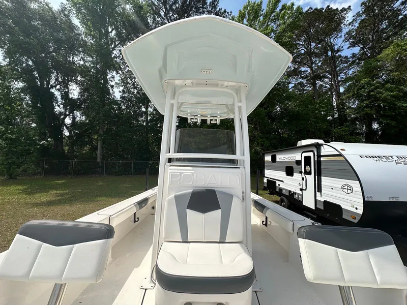 Slide: The Image of 2023 Robalo 226 Cayman boat with center console, surrounded by trees and a camper. - 8