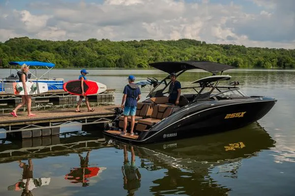 Slide: The Image of 2025 Yamaha Boats 255XD docked on a serene lake with people boarding. - 3