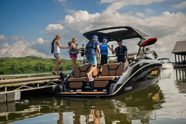 Slide: The Image of 2025 Yamaha Boats 255XD with people boarding at a scenic dock. - 4