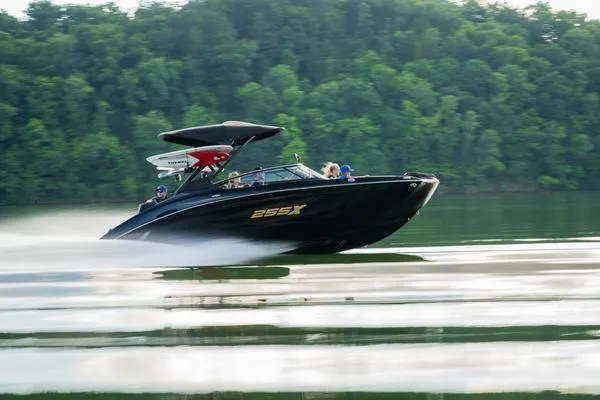 Slide: The Image of 2025 Yamaha Boats 255XD speeding on a lake with lush green forest backdrop. - 5
