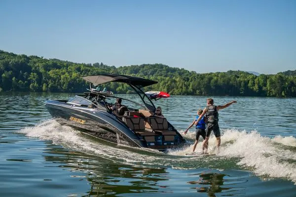 Slide: The Image of 2025 Yamaha Boats 255XD on a lake, towing a wakeboarder, surrounded by lush greenery. - 9