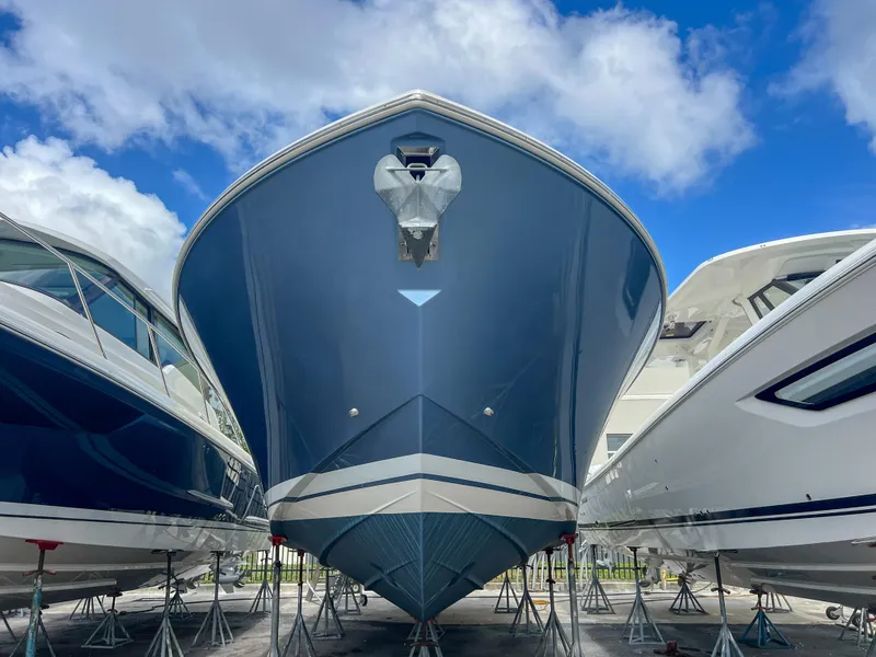 Slide: The Image of 2023 Tiara Yachts 38 LS boat on stands, viewed from the front under a blue sky. - 1