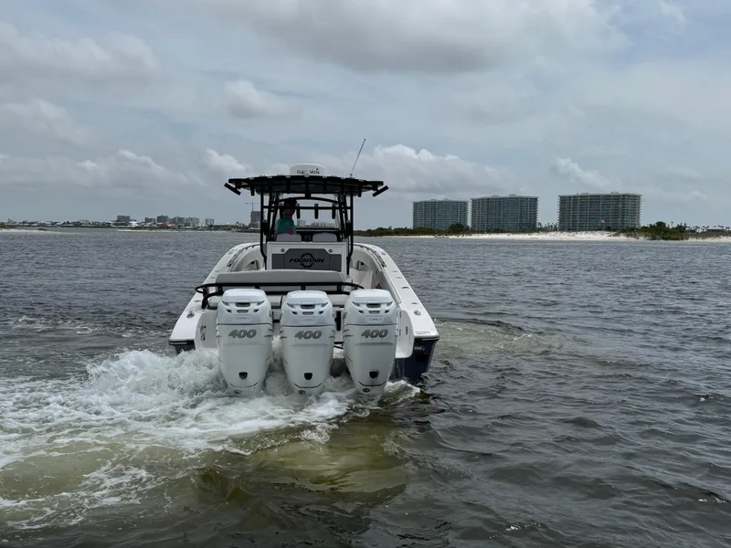 Slide: The Image of 2022 Fountain 38TE boat with triple 400 engines cruising on water near shoreline. - 14