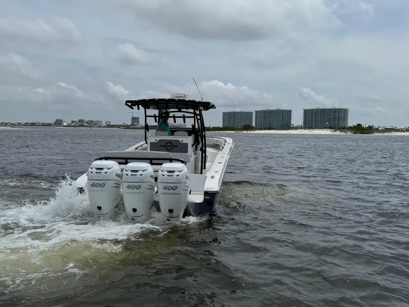 Slide: The Image of 2022 Fountain 38TE boat with triple engines cruising on open water near shoreline buildings. - 15