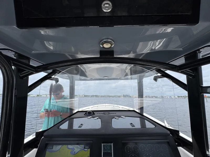 Slide: The Image of 2022 Fountain 38TE boat interior with navigation system, person visible outside on water. - 31