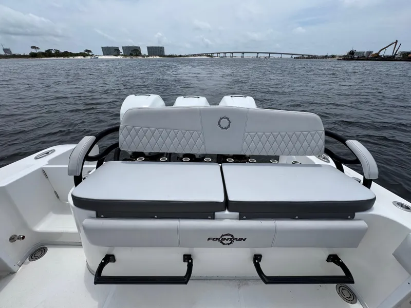 Slide: The Image of 2022 Fountain 38TE boat with cushioned seating, overlooking a scenic waterfront view. - 38