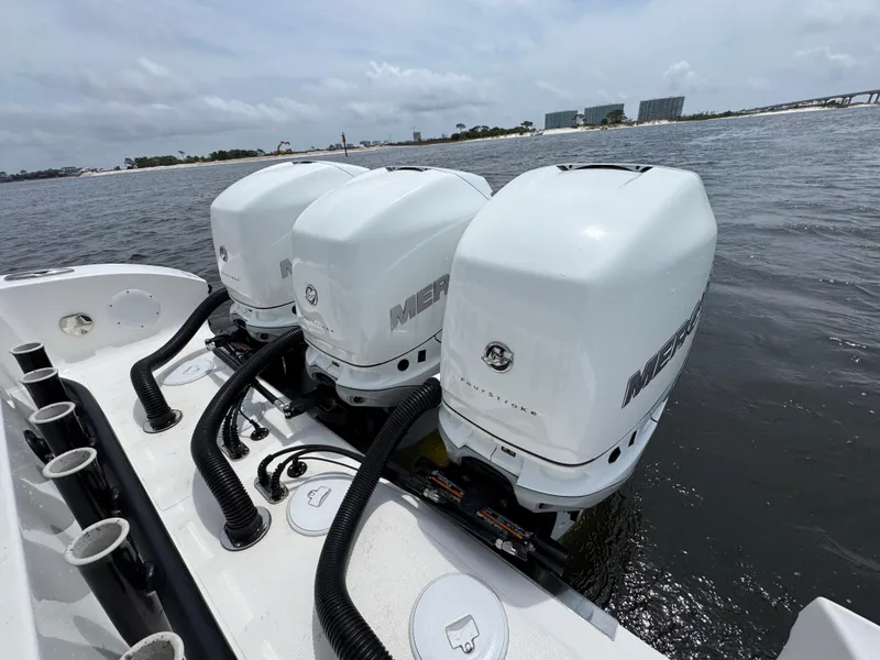 Slide: The Image of Triple Mercury outboard engines on a 2022 Fountain 38TE boat, docked on a calm waterway. - 40